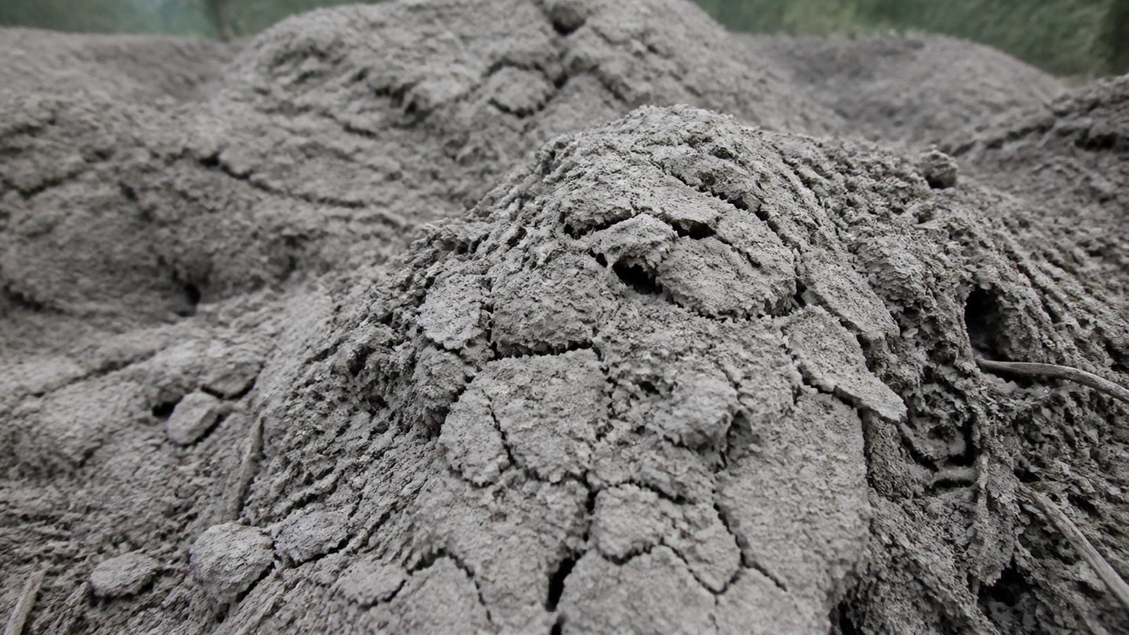 A dry dusty grey compost pile with cracked crumbling material, compost too dry